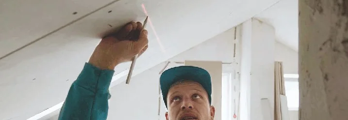 Person zeichnet Linie an Dachschräge